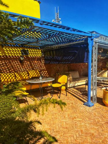 a patio with a table and chairs under a pergola at Riad Majorelle in Rabat