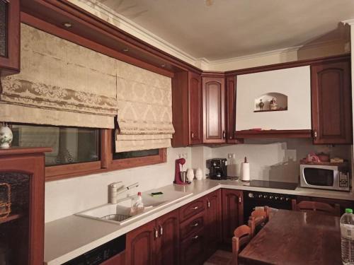 a kitchen with wooden cabinets and a sink and a microwave at VILLA ΚΟΡΑΛΙΑ in Tripolis