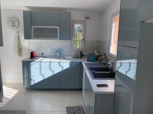 eine Küche mit blauen Schränken und einem Waschbecken in der Unterkunft Les cigales in Saint-Raphaël