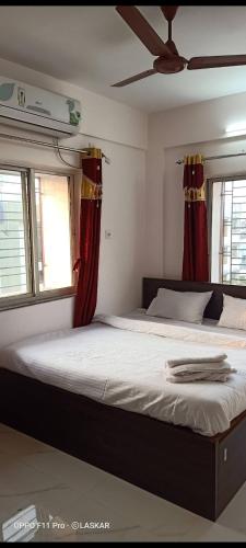 um quarto com uma cama grande e cortinas vermelhas em OYO Cv Guest House Near Rdb Cinemas em Calcutá
