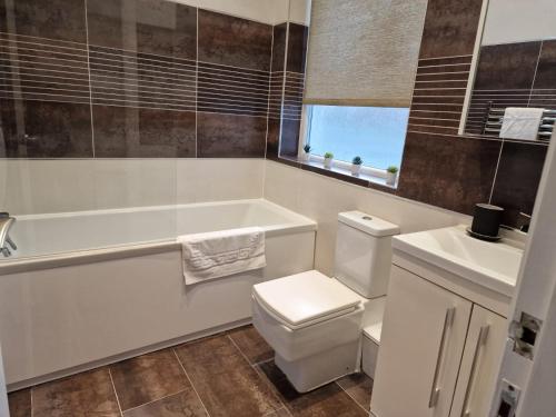 a bathroom with a tub and a toilet and a sink at Newly Furnished Close to City Centre in Hunslet