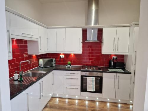 a kitchen with white cabinets and red tiles at Newly Furnished Close to City Centre in Hunslet