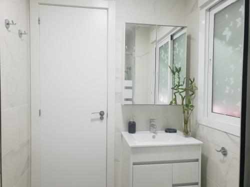 une salle de bain blanche avec un lavabo et un miroir dans l'établissement Apartment the Best Weather, à Torremolinos