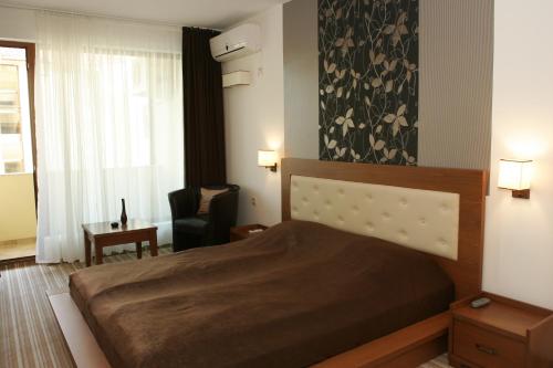 a bedroom with a bed and a chair and a window at Villa Valeev in Sozopol
