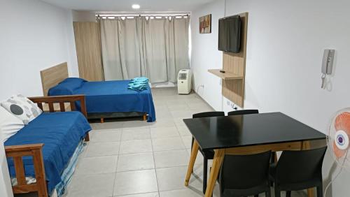 Habitación con 2 camas, mesa y TV. en FARO PLAZA RIVADAVIA Alta Cordoba en Córdoba