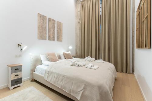 een slaapkamer met een wit bed en handdoeken bij High ceiling gem in heart of Malaga historic district in Málaga