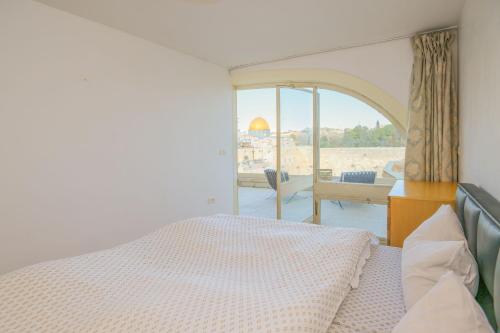 a bedroom with a bed and a window with a view at Western Wall View Apartment in Yerushalayim
