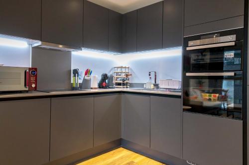 a kitchen with gray cabinets and a counter top at Pass the Keys Cosy Studio flat with a Balcony in London