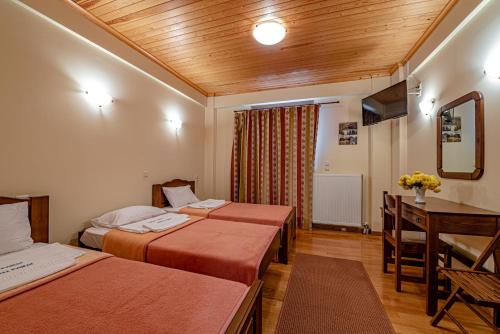 a hotel room with two beds and a desk at Xenonas Kypseli in Kipseli