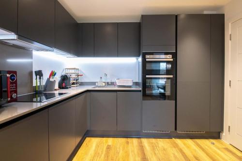 a kitchen with black cabinets and a wooden floor at Modern, Light-Filled Studio in Trendy North London in London