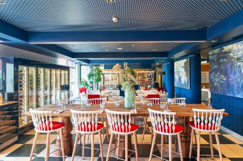 a restaurant with a large wooden table and chairs at Best Western Plus Hôtel Le Rhénan & Restaurant Chez Claude in Dorlisheim