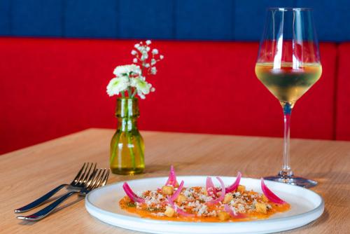 a plate of food and a glass of wine on a table at Best Western Plus Hôtel Le Rhénan & Restaurant Chez Claude in Dorlisheim