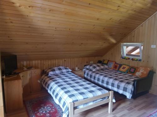 two beds in a cabin with wooden walls at Podklanci in Knežak