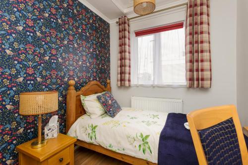 1 dormitorio con cama y papel pintado con motivos florales en Blue Sparrow House - parking en Portsmouth