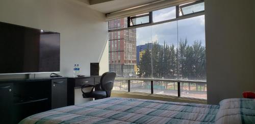 a bedroom with a bed and a large window at Suite de lujo en excelente sector, netflix, disney plus in Quito