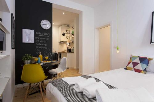 um quarto com uma cama, uma mesa e um relógio em Green Centro da Cidade Ar Condicionado em Lisboa