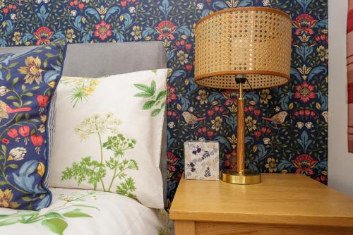 a lamp on a night stand next to a bed with a pillow at Blue Sparrow House - parking in Portsmouth