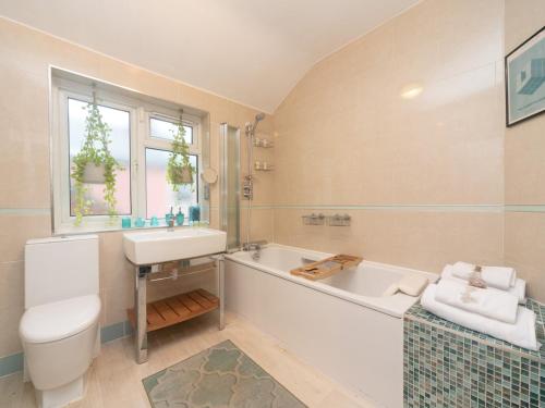 a bathroom with a tub and a sink and a toilet at Pass the Keys Beautiful Spacious Home in London