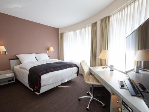 ein Hotelzimmer mit einem Bett und einem Schreibtisch in der Unterkunft DORMERO Hotel Dessau-Roßlau in Dessau