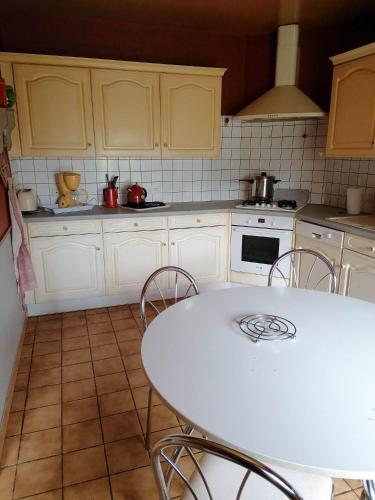 une cuisine avec une table blanche et un comptoir blanc dans l'établissement ST MALON SUR MEL, à Saint-Malon-sur-Mel