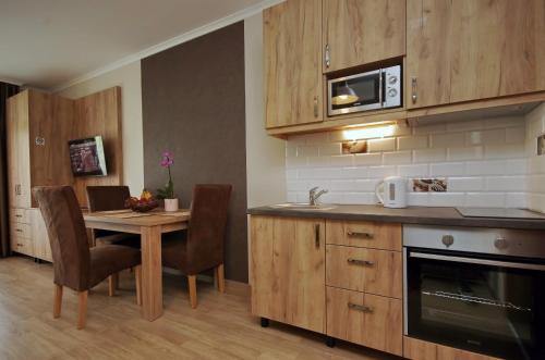 uma cozinha com uma mesa e cadeiras e um micro-ondas em Almásy Apartmanház Gyula em Gyula