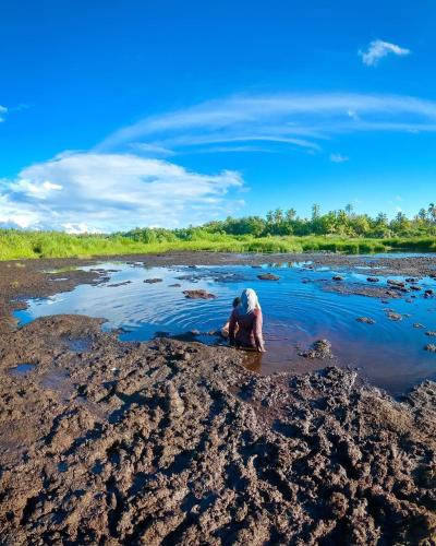 a man kneeling in the mud in a river at Endhaa, Divers Home in Fuvahmulah
