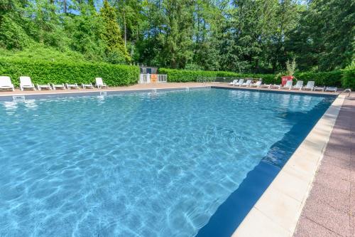 une grande piscine avec des chaises et des arbres dans l'établissement MOBIL HOME LE JACKSON 2, à Mirgaudon