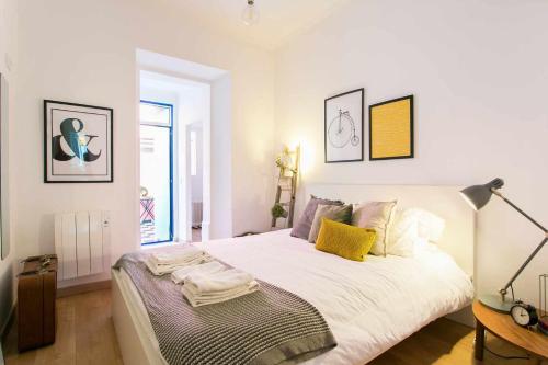 a bedroom with a large white bed with yellow pillows at St Amaro- Chic Terrace Studio Lisbon Congress in Lisbon