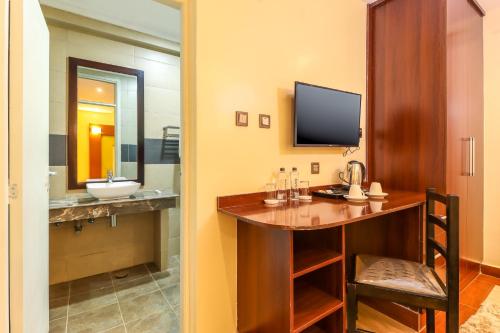 ein Bad mit einem Waschtisch mit einem Waschbecken und einem TV in der Unterkunft Dallas Premiere Hotel in Kisii