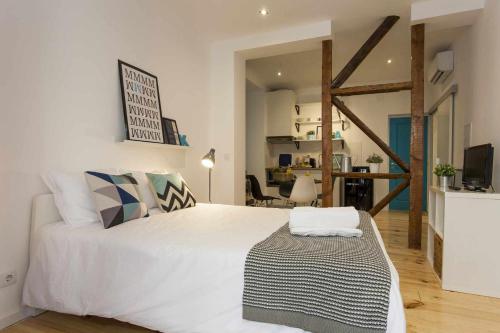 a bedroom with a large white bed and a living room at Blue Centro da Cidade Ar Condicionado in Lisbon