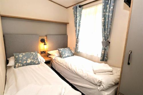 ein kleines Zimmer mit 2 Betten und einem Fenster in der Unterkunft Broadway Drive 3 in South Cerney