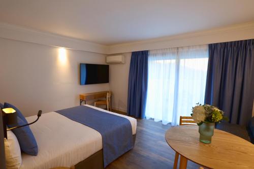 a hotel room with a bed and a table at Résidence Carlton - Rénovée avec Piscine in Beaulieu-sur-Mer