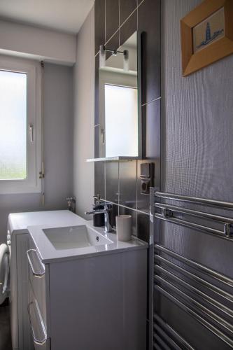 une salle de bain avec un lavabo et un miroir dans l'établissement L'Abstrait - T3 avec parking à 5 minutes du port, à Vannes