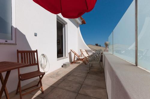 einen Balkon mit Stühlen und Tischen auf einem Gebäude in der Unterkunft Apartamento na Vila in Fão