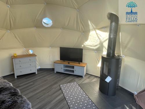 a room with a stove in a tent at Glamping Dome Elysian Fields in Helston