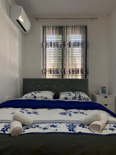 a bed with blue and white sheets and a window at Apartman EN in Trebinje