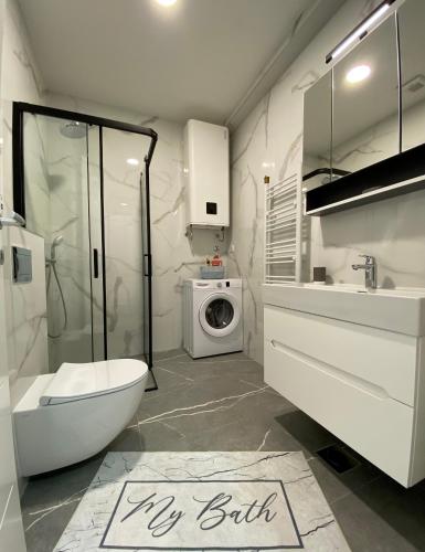 a bathroom with a toilet sink and a washing machine at Apartman EN in Trebinje