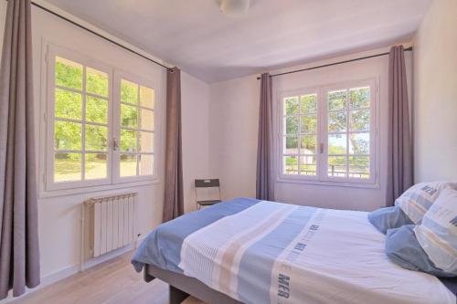 1 dormitorio con 1 cama y 2 ventanas en Maison au calme grand jardin privé aire de jeux Lac de Guerledan en Plouguernével