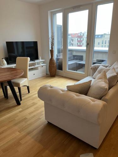 ein Wohnzimmer mit einem weißen Sofa und einem Tisch in der Unterkunft Gemütliches Appartement am Völkerschlachtdenkmal in Leipzig