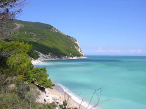 a beach with blue water and trees on a hill at The Cherry House, Apartamento Monterosa in Petritoli