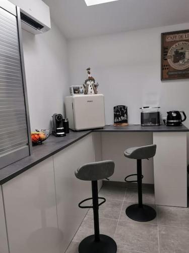 a kitchen with two stools in front of a counter at Angoulême Nord location Chambre indépendante in Champniers