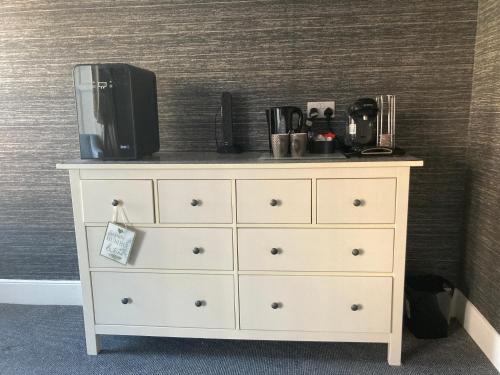 a white dresser with a tv on top of it at The Woodszz guest house in Whitby