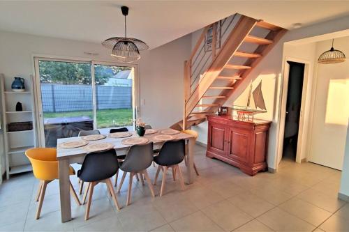 une salle à manger avec une table et des chaises et un escalier dans l'établissement La villa Breizh 'île, à Saint-Gildas-de-Rhuys