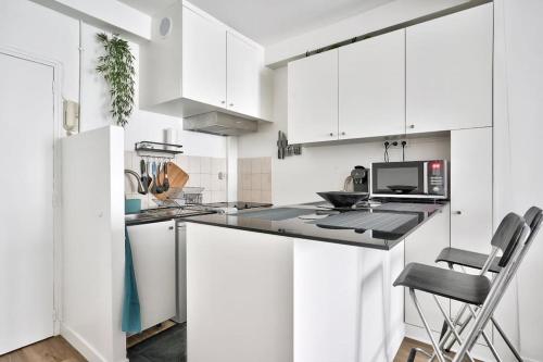 - une cuisine blanche avec des placards blancs et une chaise dans l'établissement Nice 1 BR Flat 10 min from Place de la Bastille, à Paris