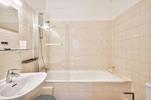 une salle de bain avec une baignoire blanche et un lavabo dans l'établissement Nice 1 BR Flat 10 min from Place de la Bastille, à Paris