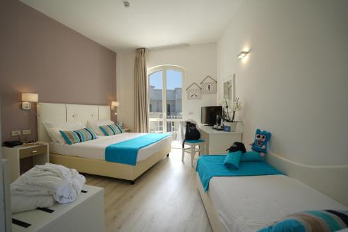 een hotelkamer met 2 bedden en een bureau bij Nicolaus Prime Il Gabbiano Hotel in Pulsano
