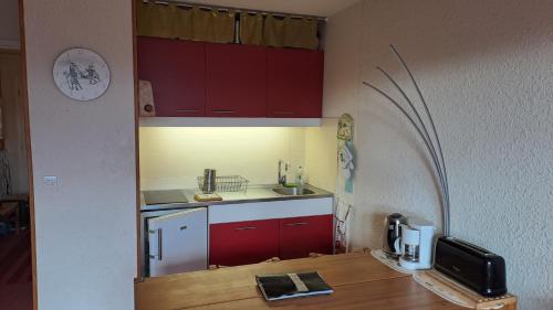 a small kitchen with red cabinets and a microwave at le Vercors en toute simplicite in Autrans