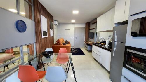 sala de estar con mesa de cristal y sillas de color naranja en Estúdio Ultra Luxo com Vista Panorâmica, en Campo Grande