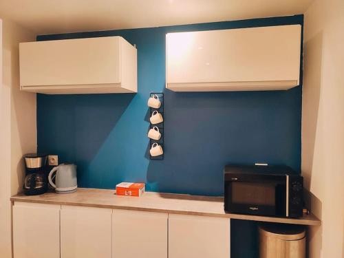 a kitchen with white cabinets and a black microwave at Maison chaleureuse située à Saumur in Saumur