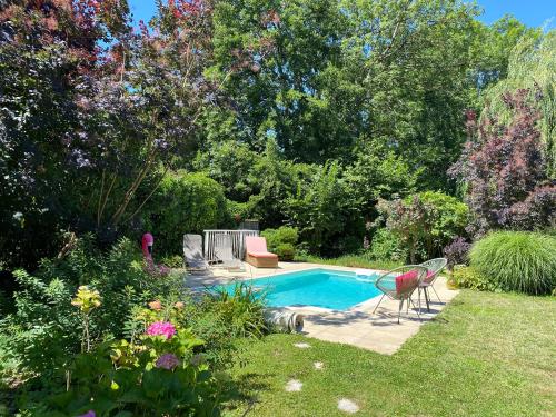 een zwembad in een tuin met een stoel en bloemen bij Au fil de L'Ouanne 